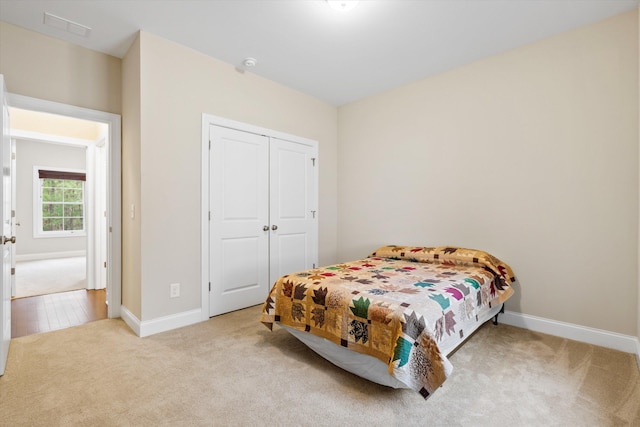 bedroom featuring carpet, visible vents, baseboards, and a closet