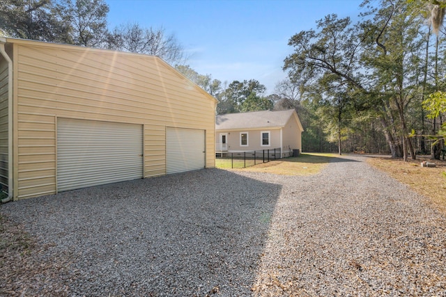 view of front of home featuring a garage, an outdoor structure, and fence