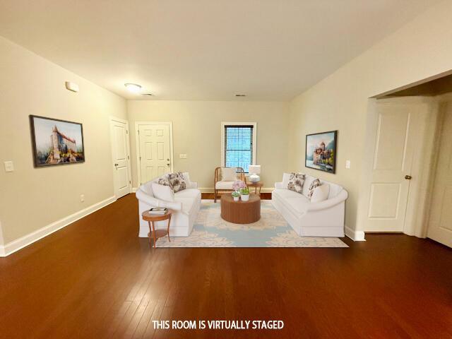 unfurnished living room with baseboards and dark wood-type flooring