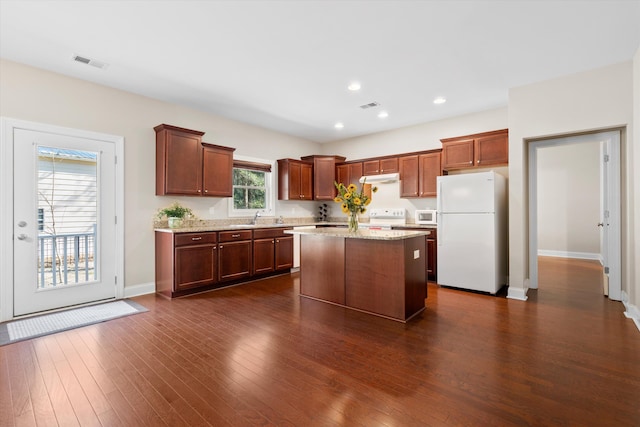 kitchen featuring dark wood-style floors, white appliances, visible vents, and a sink