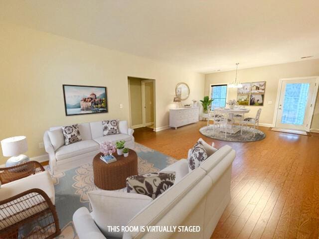 living area with hardwood / wood-style flooring, baseboards, and a notable chandelier