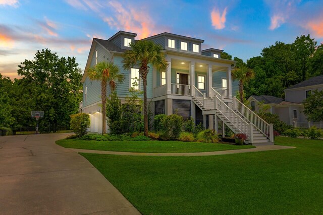 view of front of home featuring covered porch, a front yard, and a garage