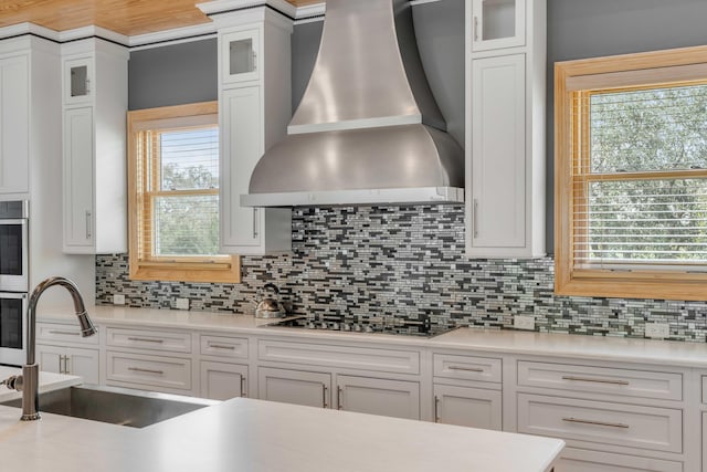 kitchen featuring white cabinetry and wall chimney range hood