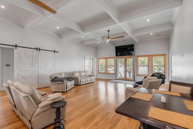 living room with beam ceiling, a barn door, light hardwood / wood-style floors, and a healthy amount of sunlight