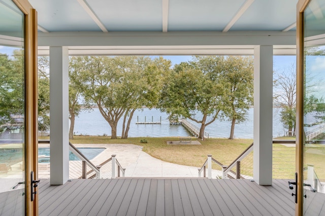 wooden deck featuring a water view, a patio area, and a lawn