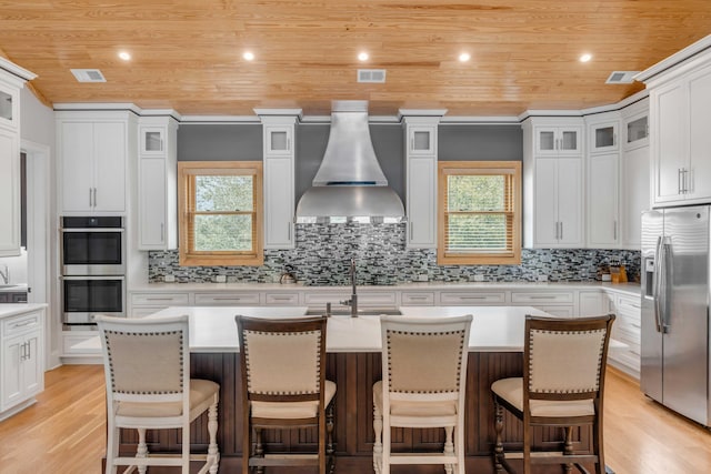 kitchen featuring an island with sink, stainless steel appliances, and light wood-type flooring