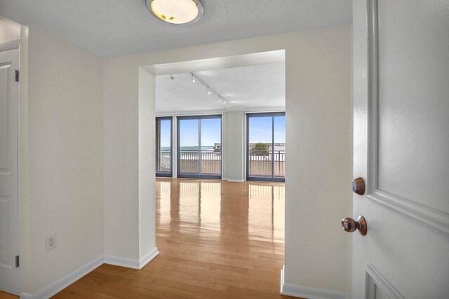 hall featuring expansive windows, hardwood / wood-style flooring, and track lighting