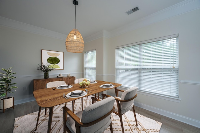 dining room featuring light wood-style floors, baseboards, ornamental molding, and visible vents