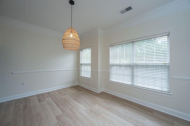 spare room with light wood-style floors, baseboards, ornamental molding, and visible vents