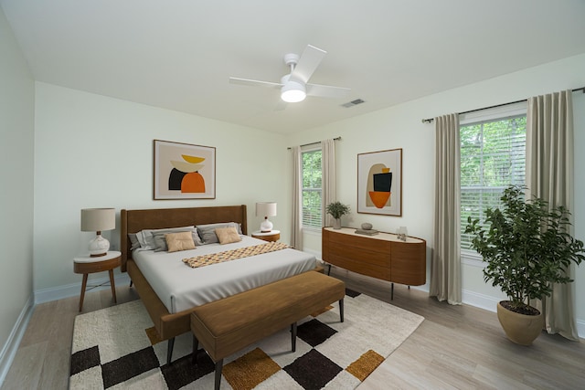 bedroom with baseboards, visible vents, multiple windows, and light wood-style floors