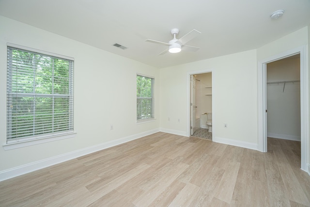 unfurnished bedroom with visible vents, light wood-type flooring, baseboards, a closet, and a spacious closet