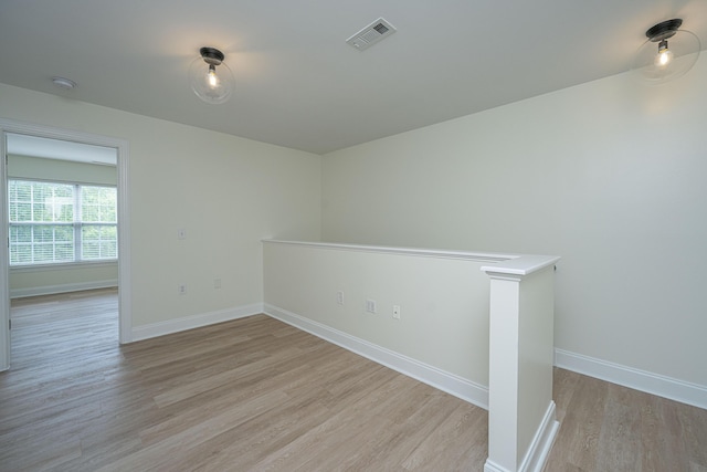 unfurnished room featuring baseboards, visible vents, and light wood finished floors