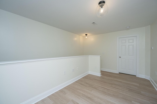 unfurnished room featuring baseboards, light wood-style flooring, and visible vents