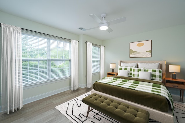 bedroom featuring baseboards, ceiling fan, wood finished floors, and visible vents