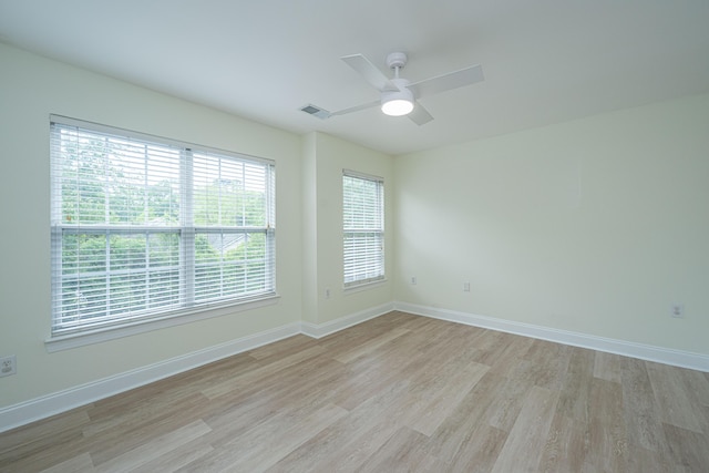 empty room featuring light wood-style floors, baseboards, ceiling fan, and visible vents