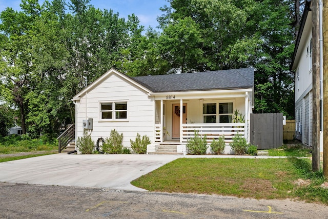 view of front of home with covered porch, fence, and roof with shingles