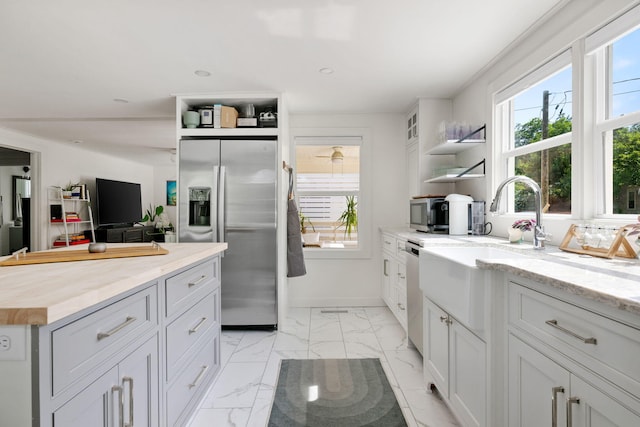 kitchen with appliances with stainless steel finishes, open shelves, plenty of natural light, light marble finish floors, and recessed lighting