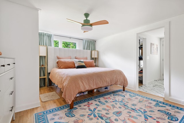 bedroom with ceiling fan, baseboards, and light wood-style floors