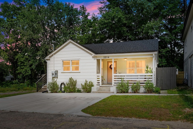 view of front of property with a porch, a shingled roof, and fence