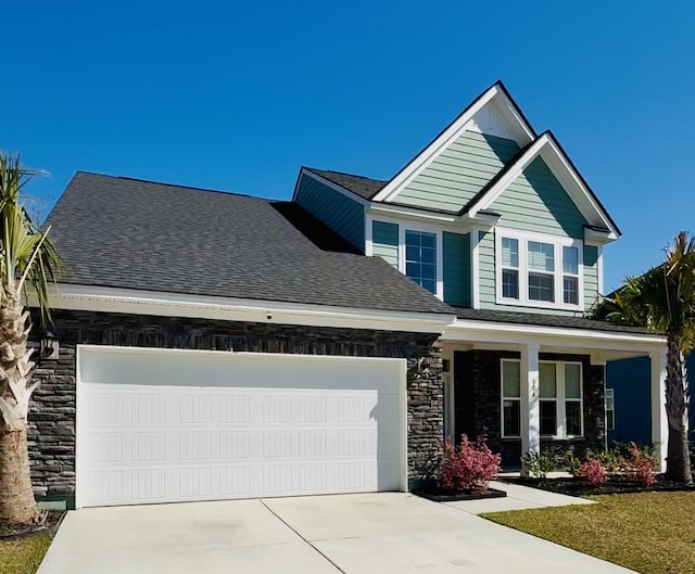 craftsman house featuring a garage, stone siding, driveway, and a shingled roof