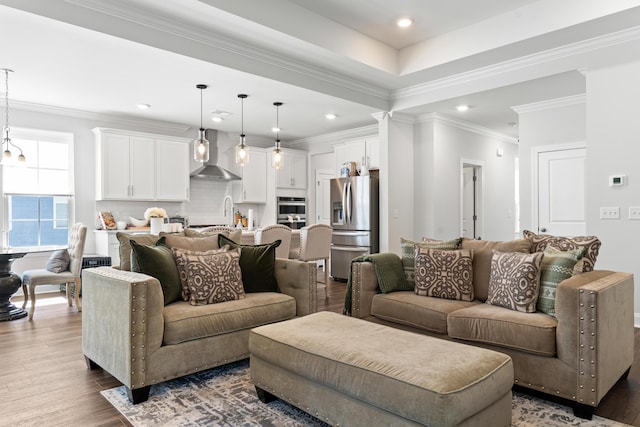 living area with recessed lighting, ornamental molding, an inviting chandelier, and wood finished floors