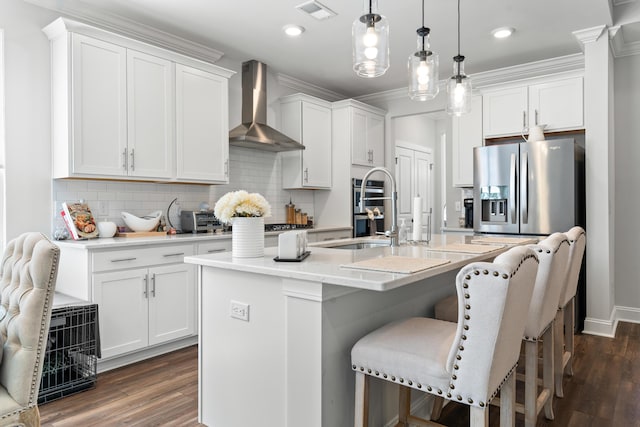 kitchen with dark wood-style floors, visible vents, appliances with stainless steel finishes, wall chimney range hood, and tasteful backsplash