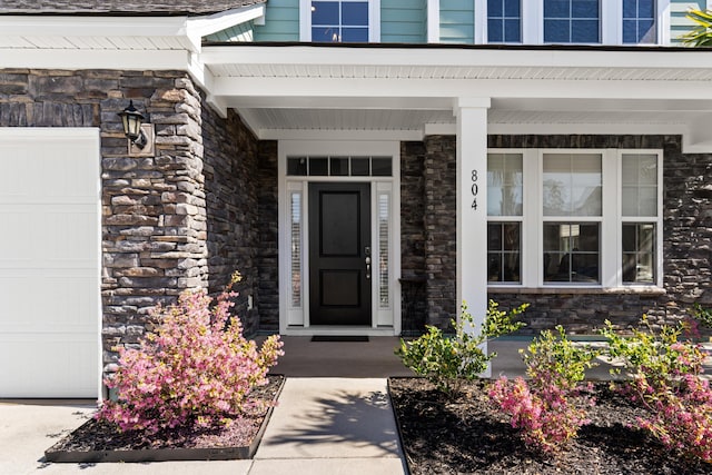 view of exterior entry with covered porch and stone siding