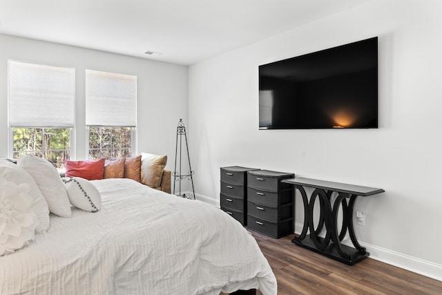 bedroom with visible vents, baseboards, and dark wood finished floors