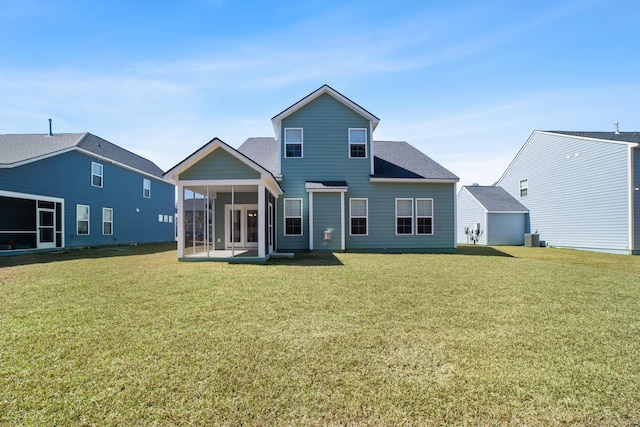 back of property with a yard, cooling unit, a sunroom, and a shingled roof