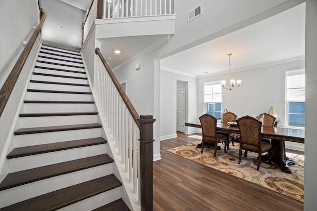 stairs with visible vents, crown molding, baseboards, a chandelier, and wood finished floors