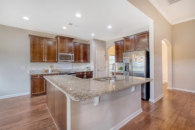 kitchen featuring sink, stainless steel appliances, dark hardwood / wood-style flooring, an island with sink, and ornamental molding