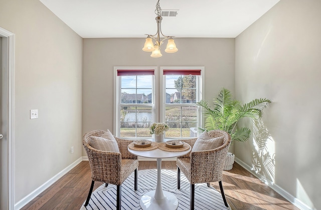 dining room with a water view, a notable chandelier, and hardwood / wood-style flooring