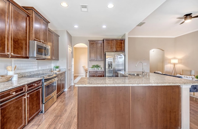 kitchen with an island with sink, stainless steel appliances, light hardwood / wood-style flooring, and sink