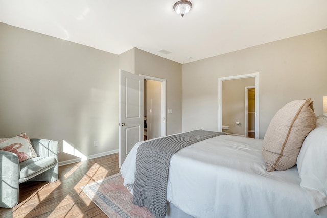 bedroom featuring connected bathroom and hardwood / wood-style flooring