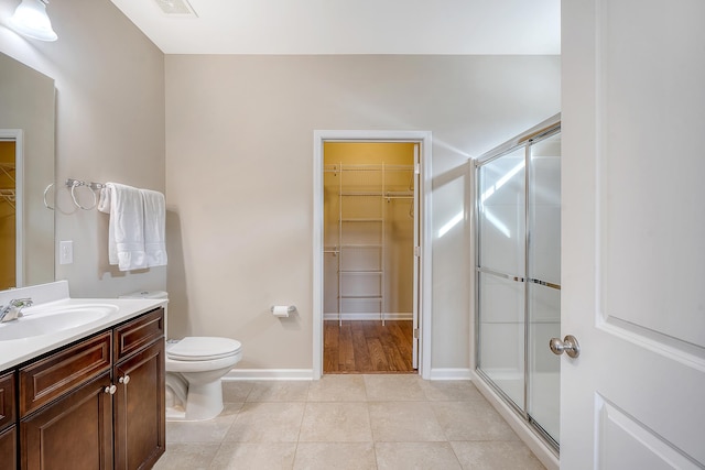 bathroom featuring toilet, a shower with door, vanity, and tile patterned flooring