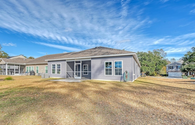 back of property with a sunroom, a yard, and central AC