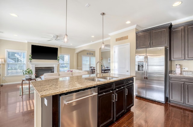 kitchen with pendant lighting, dark hardwood / wood-style floors, sink, a center island with sink, and appliances with stainless steel finishes