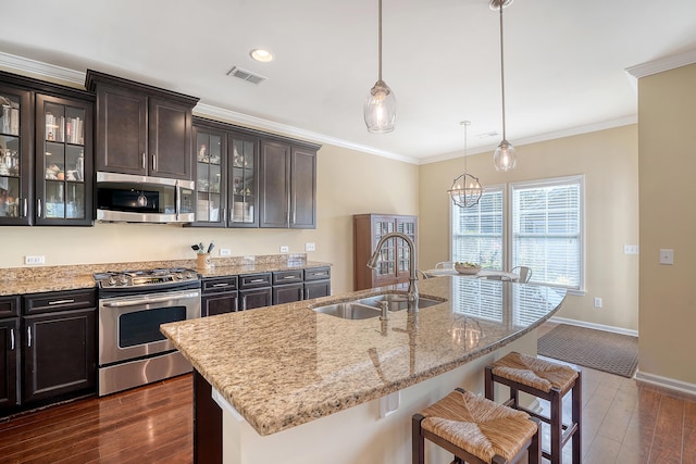 kitchen featuring appliances with stainless steel finishes, hanging light fixtures, dark wood-type flooring, dark brown cabinets, and sink