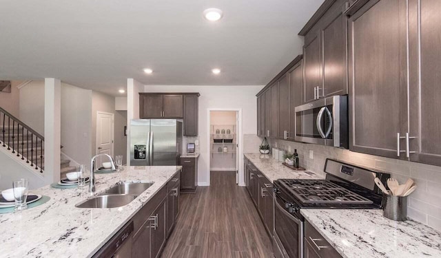 kitchen featuring sink, appliances with stainless steel finishes, light stone counters, tasteful backsplash, and dark brown cabinetry