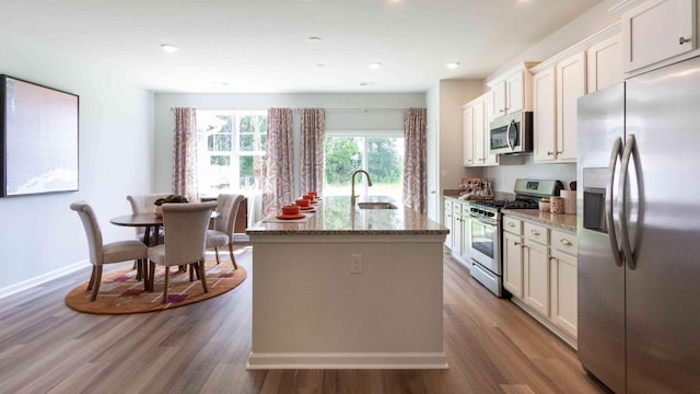 136 Yarrow Way, Moncks Corner, SC 29461 - kitchen with appliances with stainless steel finishes, a sink, wood finished floors, stone counters, and a kitchen island with sink