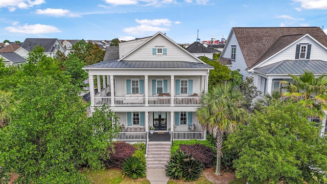 view of front of home featuring a porch, stairway, a balcony, a standing seam roof, and metal roof