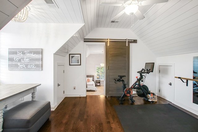 workout area featuring a barn door, visible vents, a ceiling fan, wood finished floors, and vaulted ceiling