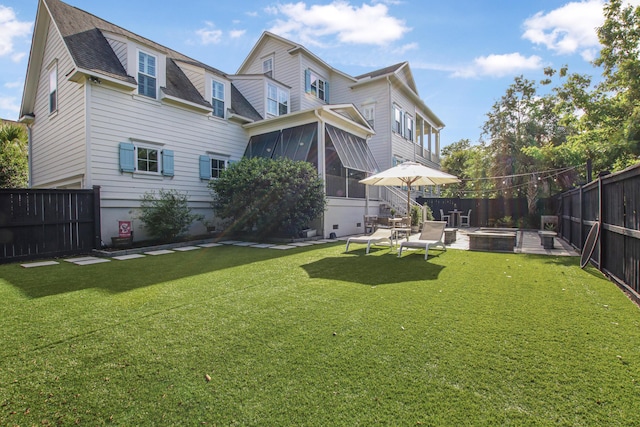 rear view of property with a shingled roof, a sunroom, a fenced backyard, a lawn, and a patio
