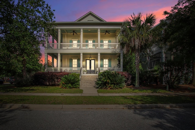 view of front of home featuring covered porch, ceiling fan, a front yard, and a balcony