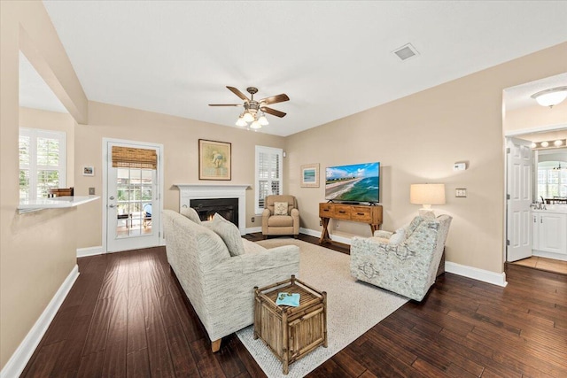 living room with dark hardwood / wood-style floors, ceiling fan, and a healthy amount of sunlight