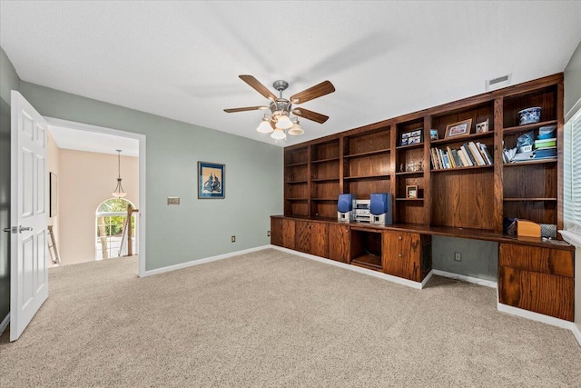 office space featuring built in shelves, ceiling fan, and carpet floors