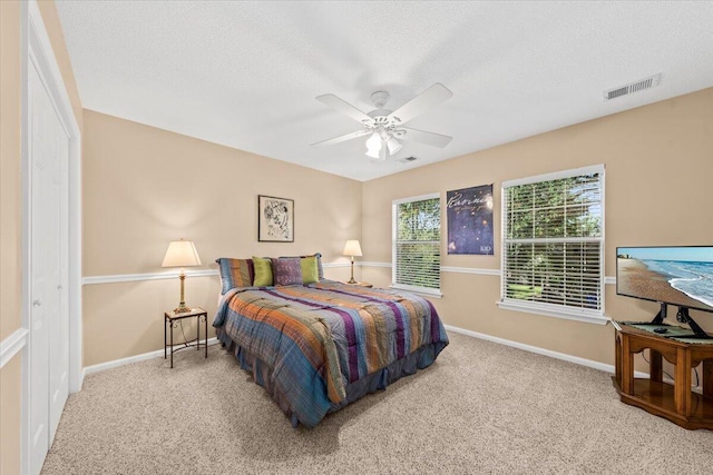 carpeted bedroom with ceiling fan, a textured ceiling, and a closet