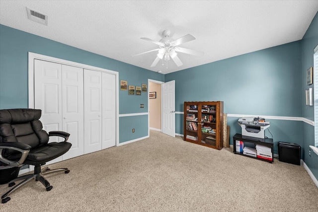 carpeted office featuring ceiling fan and a textured ceiling