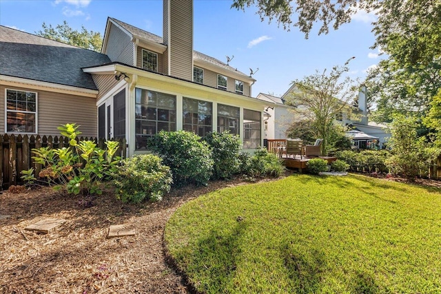 back of house featuring a sunroom and a lawn