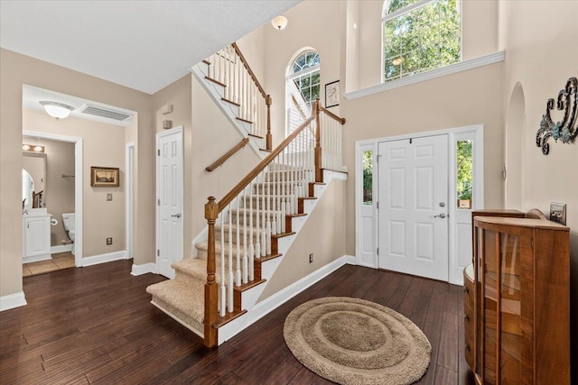 entrance foyer with a towering ceiling and dark hardwood / wood-style floors